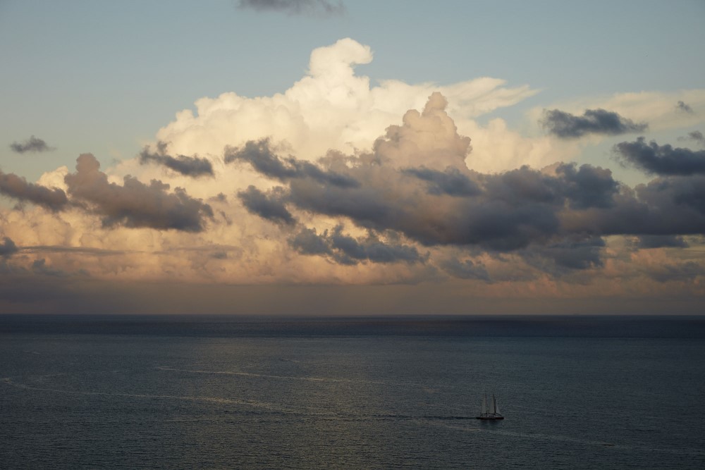Drone view of a sail boat in the Atlantic ocean under big clouds